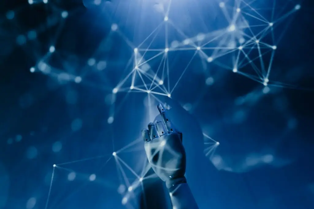 Free A robotic hand reaching into a digital network on a blue background, symbolizing AI technology. Stock Photo